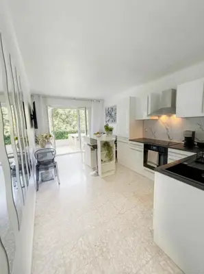 a kitchen with white cabinets and a table and a chair at Long Beach Apartment Cannes in Cannes