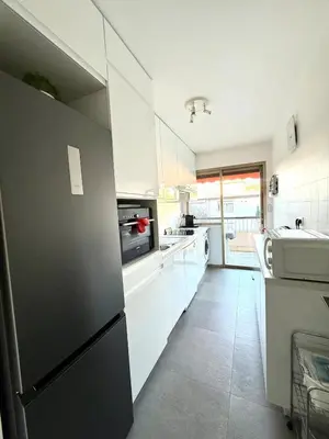 a kitchen with white cabinets and a black refrigerator at T2 derrière le Martinez - Croisette in Cannes