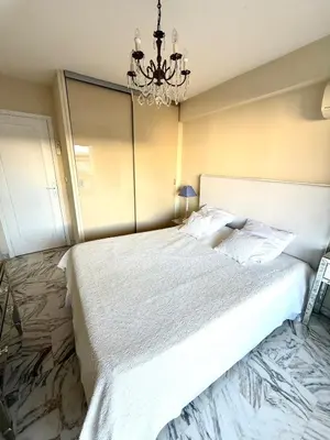 a bedroom with a large white bed with a chandelier at T2 derrière le Martinez - Croisette in Cannes