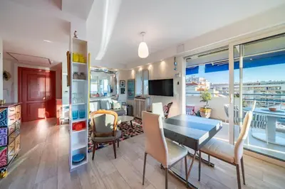 a living room with a table and chairs and a balcony at Top floor 3 Bedroom near the Croisette in Cannes