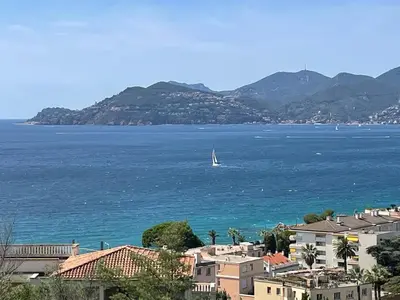 a sail boat in the water with houses and mountains at Splendid view Apartment in Cannes in Cannes