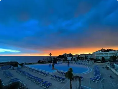 a view of a swimming pool with chairs and the ocean at Vue mer piscine parking tennis 4 personnes in Cannes