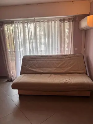 a couch sitting in front of a window with curtains at Studio Palais Rouaze-50m de la Croisette in Cannes