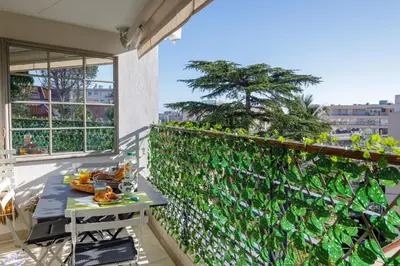 a table on a balcony with a green wall at Villa Lerins 411 by Halldis in Cannes
