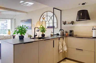 a kitchen with white cabinets and a black counter top at Villa Lerins 411 by Halldis in Cannes