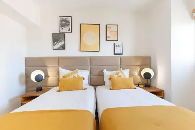 two beds in a bedroom with yellow pillows at Villa Lerins 304 by Halldis in Cannes