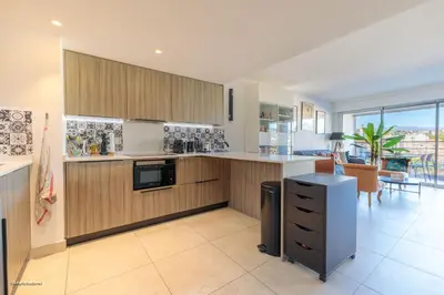 a kitchen with wooden cabinets and a large window at Villa Lerins 405 by Halldis in Cannes
