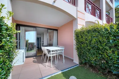 a table and chairs on a patio with a garden at Vue Mer - Piscine - Tennis - 2P avec Jardin - Cannes in Cannes