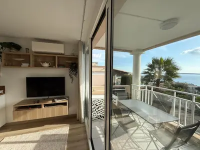 a living room with a balcony with a tv and a balcony at CasaMia Cannes - Exceptional Sea View, Pool, Beach in Cannes