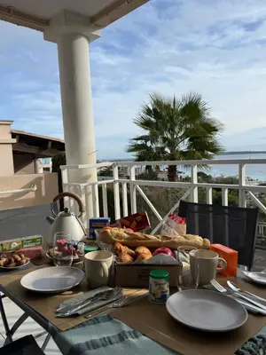 a table with a plate of food on a balcony at CasaMia Cannes - Exceptional Sea View, Pool, Beach in Cannes