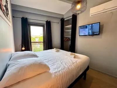 a bedroom with a bed with a television and a window at Appart 3 chambres, Cannes centre & plages in Cannes
