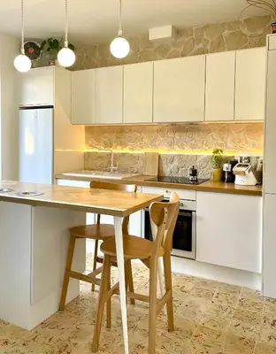 a kitchen with white cabinets and a wooden table and chairs at Terrasse des artistes - Appartement 2 pièces avec pergola in Cannes