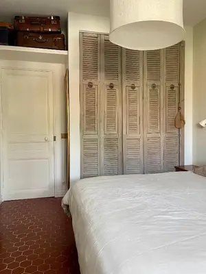 a bedroom with a white bed and wooden closet at Terrasse des artistes - Appartement 2 pièces avec pergola in Cannes