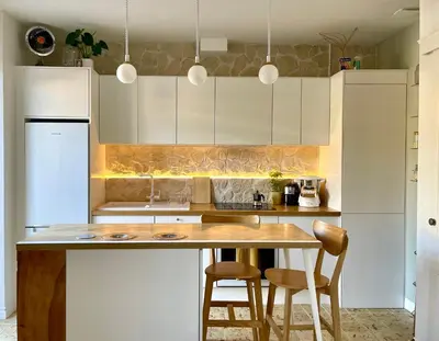 a kitchen with white cabinets and a wooden table at Terrasse des artistes - Appartement 2 pièces avec pergola in Cannes