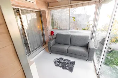 a living room with a couch in a room with windows at Private Garden Hideaway by the Sea in Cannes