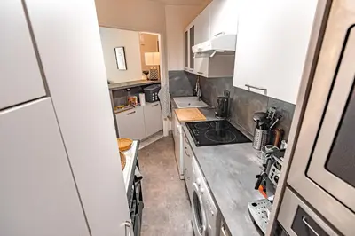 a small kitchen with white cabinets and a stove at Private Garden Hideaway by the Sea in Cannes