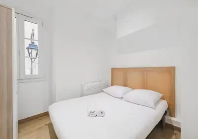 a white bed in a white room with a window at Magnifique 2 pièces au Suquet in Cannes