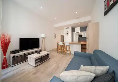 a living room with a blue couch and a tv at Parenthèse élégante au centre de Cannes in Cannes