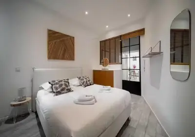 a white bedroom with a large white bed and a mirror at Parenthèse élégante au centre de Cannes in Cannes