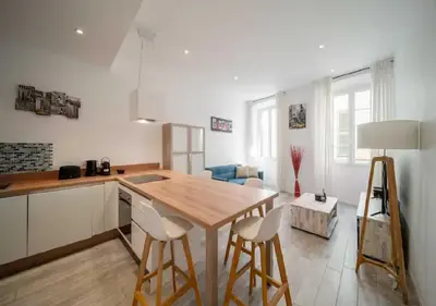 a kitchen with a wooden table and chairs in a room at Parenthèse élégante au centre de Cannes in Cannes