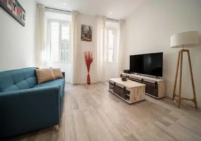 a living room with a blue couch and a flat screen tv at Parenthèse élégante au centre de Cannes in Cannes