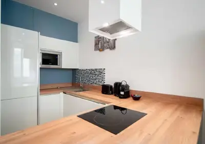 a kitchen with white cabinets and a wooden counter top at Parenthèse élégante au centre de Cannes in Cannes