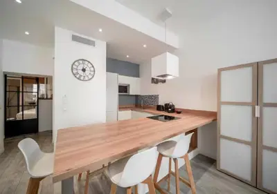 a kitchen with a wooden table and white chairs at Parenthèse élégante au centre de Cannes in Cannes