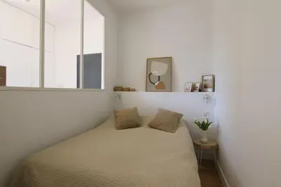 a bed in a bedroom with white walls and windows at Pearl Studio by Halldis in Cannes