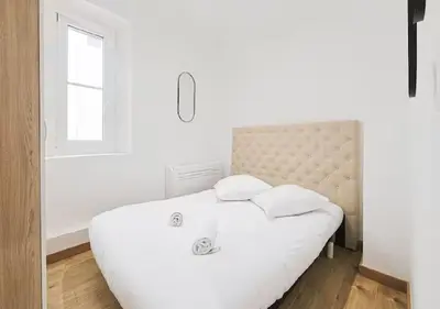 a white bedroom with a large bed and a window at Charmant deux pièces au Suquet in Cannes