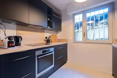 a kitchen with black cabinets and a window at 3P Garden-Level Apartment in a Residence with Pool Close to the Center in Cannes