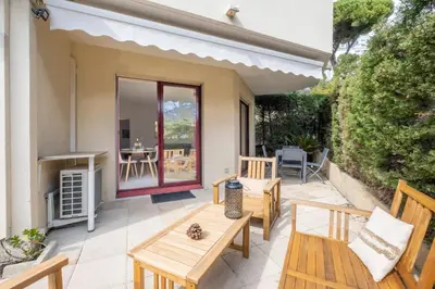 a patio with two wooden benches and a table at 3P Garden-Level Apartment in a Residence with Pool Close to the Center in Cannes