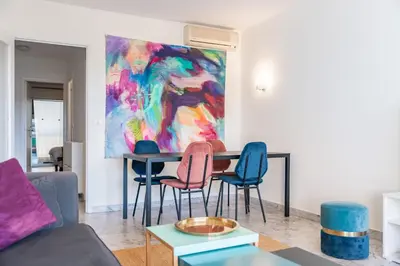 a living room with a table with chairs and a painting at Spacious 1-bedroom apartment in the heart of Cannes in Cannes