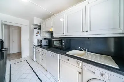 a kitchen with white cabinets and a sink at Spacious 1-bedroom apartment in the heart of Cannes in Cannes