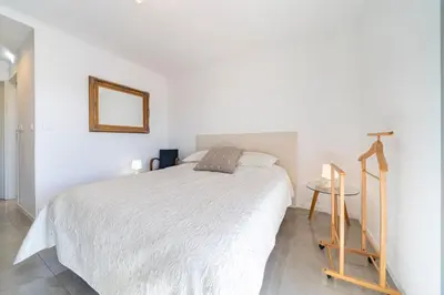 a white bedroom with a bed and a mirror at Brand new 2 bedrooms heart of Cannes in Cannes