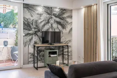 a living room with a wall mural of palm trees at Charmant appartement 2 pièces in Cannes