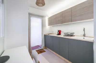 a kitchen with blue cabinets and a sink and a window at Charmant appartement 2 pièces in Cannes