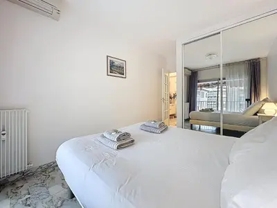 a white bedroom with a bed and a mirror at 47m2 - climatisation, carré d'or in Cannes