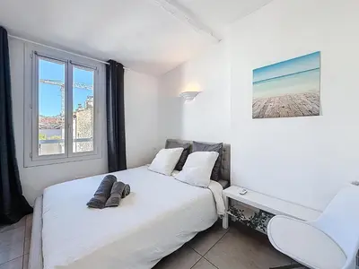 a white bedroom with a bed and a window at Vue mer 50 m plage et Croisette Cannes centre in Cannes