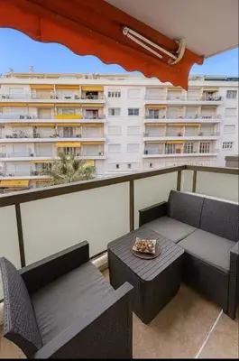 a balcony with a couch and a table and a building at Appartement rue D'antibes in Cannes