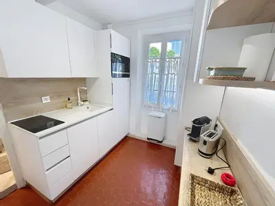 a kitchen with white cabinets and a red floor at Cosy & modern 1 Bedroom Forville old town 207 in Cannes