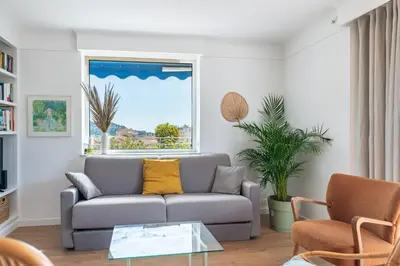 a living room with a couch and a window at 2 pièces proche centre Cannes - Vue mer panoramique - Toit terrasse in Cannes