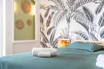 a bedroom with a green bed with a tropical wallpaper at 2 pièces proche centre Cannes - Vue mer panoramique - Toit terrasse in Cannes