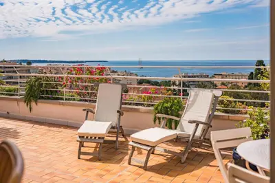 two chairs on a balcony with a view of the ocean at 2 pièces proche centre Cannes - Vue mer panoramique - Toit terrasse in Cannes