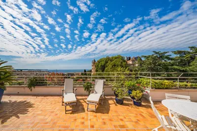 a patio with chairs and tables on a balcony at 2 pièces proche centre Cannes - Vue mer panoramique - Toit terrasse in Cannes