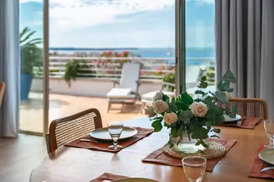 a table with a vase of flowers on top of it at 2 pièces proche centre Cannes - Vue mer panoramique - Toit terrasse in Cannes