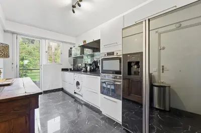 a kitchen with white cabinets and a washer and dryer at La Rose des Vents - Cannes in Cannes