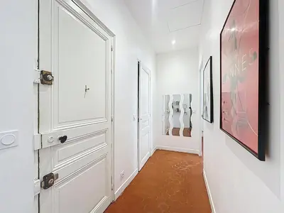 a hallway with white cabinets and a painting on the wall at 42 m2 - Close to Palais des Festivals and beaches in Cannes
