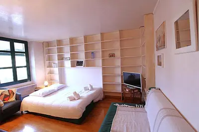 a bedroom with a bed and a couch and a television at Cannes Central Hub - Walk to Palais & Beach in Cannes