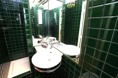 a green tiled bathroom with two sinks and a mirror at Cannes Central Hub - Walk to Palais & Beach in Cannes
