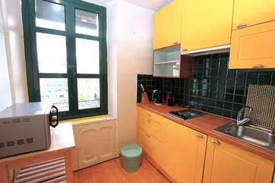 a kitchen with yellow cabinets and a sink and a window at Cannes Central Hub - Walk to Palais & Beach in Cannes